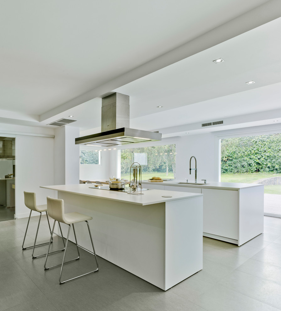 Inspiration for a large modern galley open plan kitchen in Madrid with flat-panel cabinets, white cabinets, multiple islands, grey floors and white worktops.