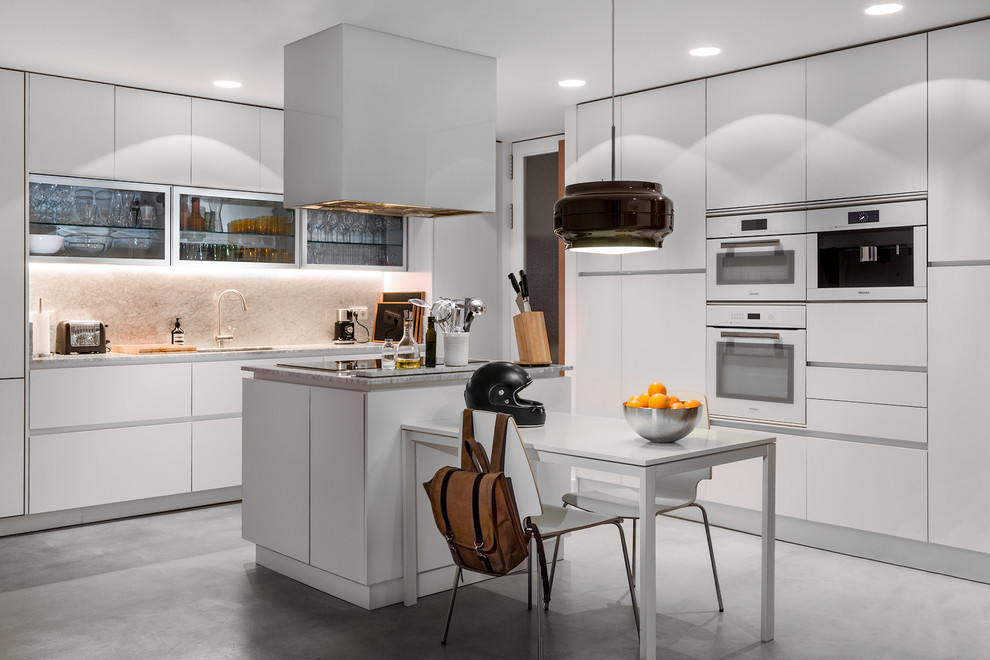 Idee per una grande cucina minimal con ante lisce, ante bianche, elettrodomestici bianchi e pavimento in cemento
