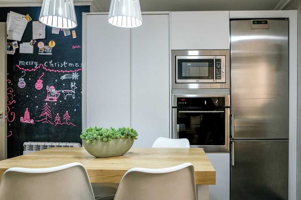Foto de cocina comedor nórdica de tamaño medio con fregadero encastrado, puertas de armario de madera oscura, electrodomésticos de acero inoxidable y suelo negro