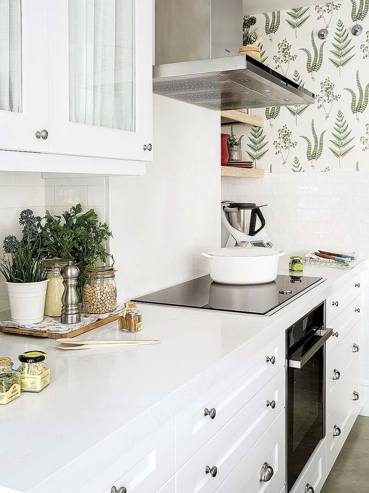 Inredning av ett shabby chic-inspirerat mellanstort vit vitt kök, med en undermonterad diskho, skåp i shakerstil, vita skåp, bänkskiva i kvarts, vitt stänkskydd, stänkskydd i tunnelbanekakel, vita vitvaror, betonggolv, en halv köksö och grått golv