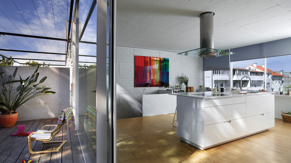 Exempel på ett modernt kök, med en undermonterad diskho, släta luckor, vita skåp, rostfria vitvaror, mellanmörkt trägolv, en köksö och brunt golv