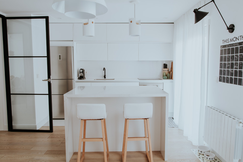 Large scandi single-wall kitchen/diner in Other with a submerged sink, flat-panel cabinets, white cabinets, engineered stone countertops, white splashback, stainless steel appliances, ceramic flooring, an island and grey floors.