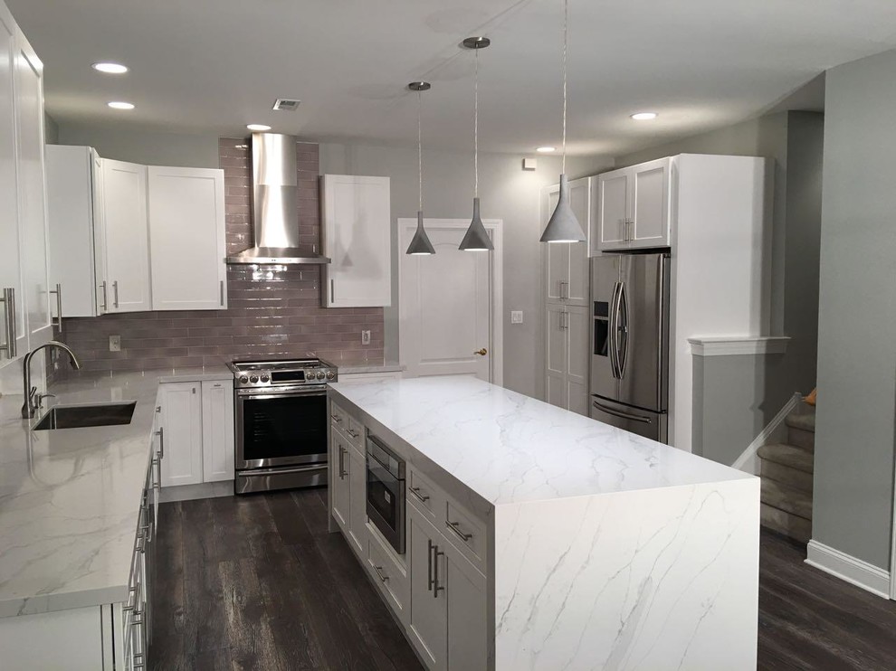 Inspiration for a mid-sized transitional l-shaped laminate floor enclosed kitchen remodel in Philadelphia with raised-panel cabinets, white cabinets, quartz countertops, black backsplash, stainless steel appliances and an island