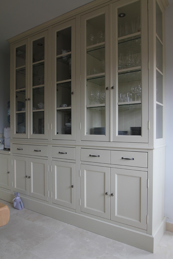 This is an example of a large farmhouse enclosed kitchen in Madrid with a built-in sink, glass-front cabinets, beige cabinets, stainless steel appliances, marble flooring, an island and beige floors.