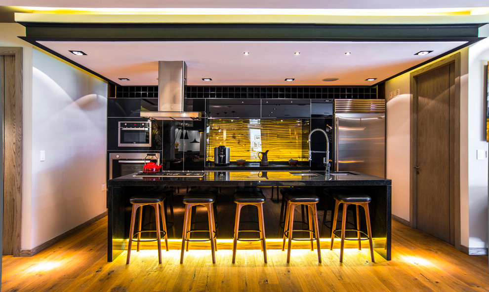 Moderne Küche mit Doppelwaschbecken, flächenbündigen Schrankfronten, schwarzen Schränken, Küchengeräten aus Edelstahl, braunem Holzboden und Kücheninsel in Mexiko Stadt