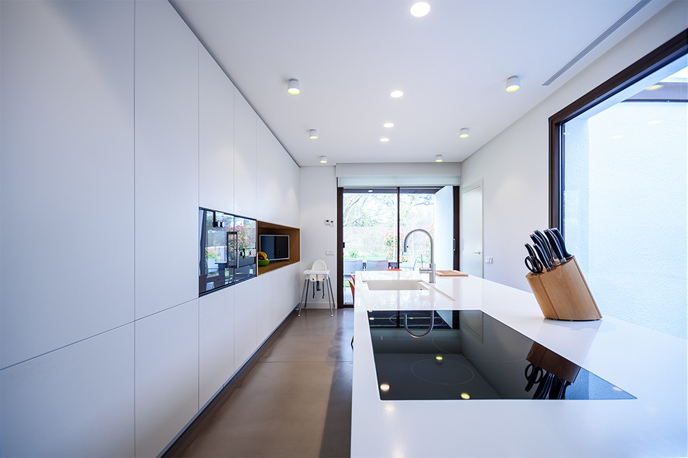 Foto på ett stort funkis vit kök och matrum, med en integrerad diskho, släta luckor, vita skåp och en köksö