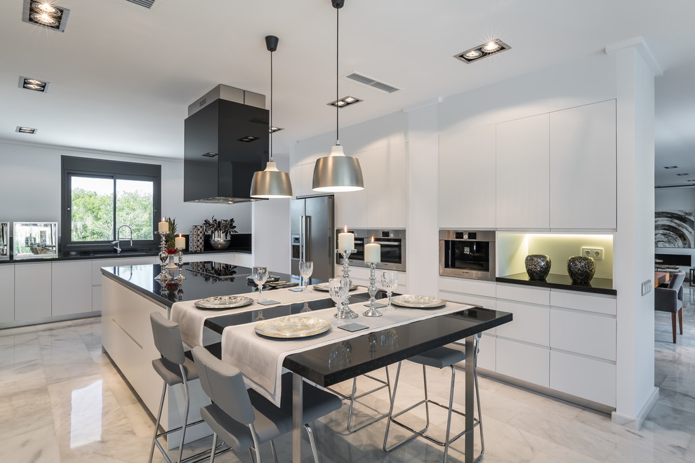 Inspiration for a large contemporary u-shaped eat-in kitchen remodel in Madrid with flat-panel cabinets, white cabinets, stainless steel appliances, an island and solid surface countertops