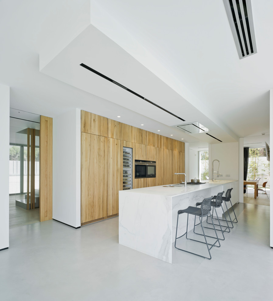 Immagine di una grande cucina minimalista con ante lisce, ante in legno scuro, elettrodomestici neri, pavimento in cemento e pavimento grigio
