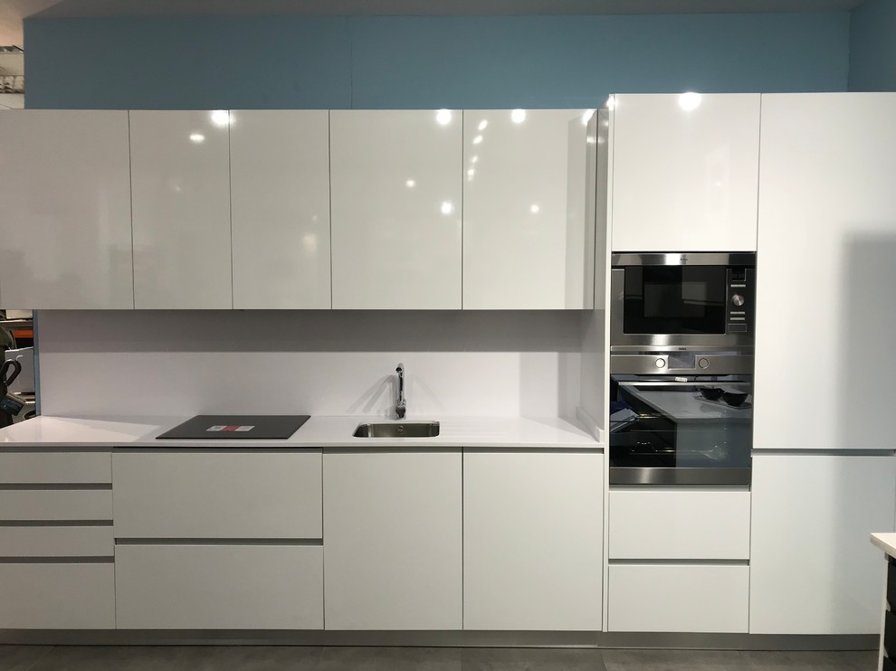 Exempel på ett litet modernt linjärt kök och matrum, med en undermonterad diskho, luckor med upphöjd panel, vita skåp, laminatbänkskiva, vitt stänkskydd, stänkskydd i stickkakel, rostfria vitvaror, marmorgolv och grått golv