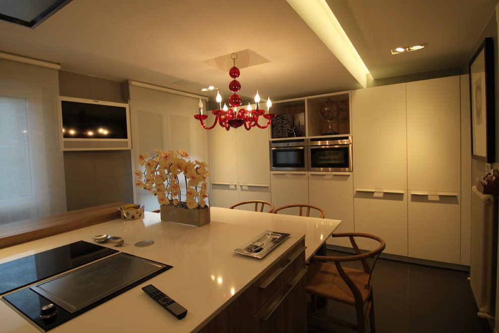 Große, Einzeilige Stilmix Wohnküche mit flächenbündigen Schrankfronten, weißen Schränken, Küchengeräten aus Edelstahl und Kücheninsel in Bilbao