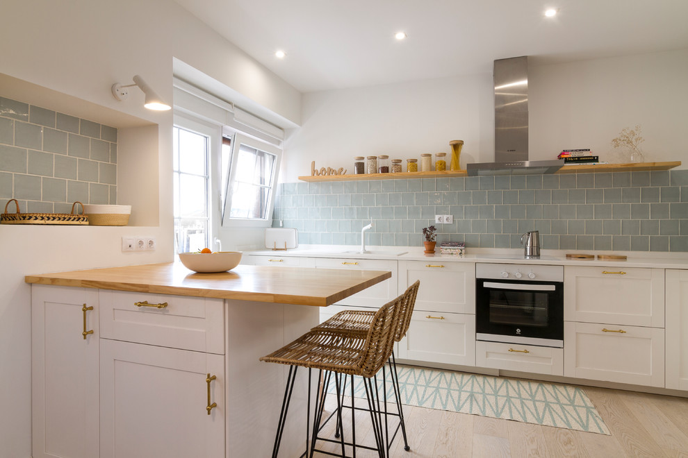 Exempel på ett skandinaviskt vit vitt kök, med en nedsänkt diskho, skåp i shakerstil, vita skåp, blått stänkskydd, ljust trägolv, en halv köksö och beiget golv