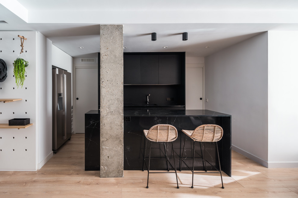 Inspiration for a contemporary l-shaped light wood floor and beige floor eat-in kitchen remodel in Other with an undermount sink, flat-panel cabinets, black cabinets, black backsplash, stainless steel appliances, an island and black countertops