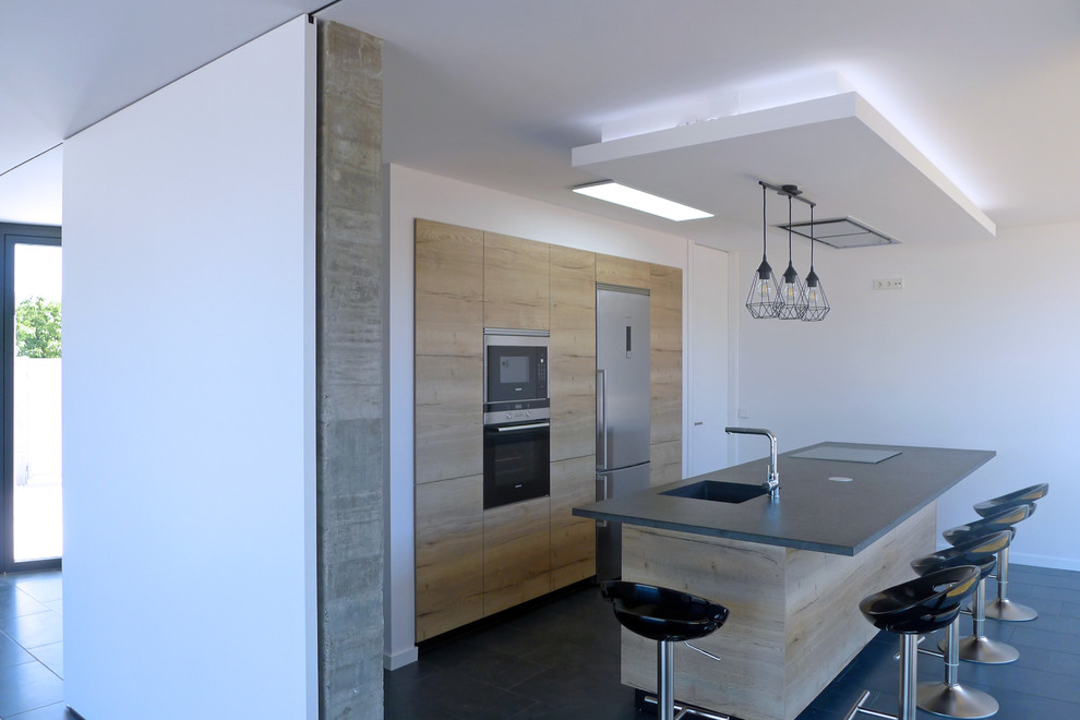 Kleine Moderne Küche mit hellen Holzschränken, Granit-Arbeitsplatte, Keramikboden, Kücheninsel, grauem Boden und schwarzer Arbeitsplatte in Sonstige