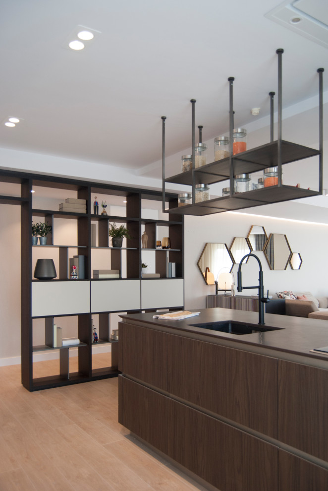 Photo of a contemporary single-wall open plan kitchen in Bilbao with a submerged sink, flat-panel cabinets, beige cabinets, quartz worktops, stainless steel appliances, an island and black worktops.