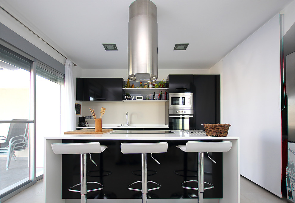 Modelo de cocina minimalista de tamaño medio con armarios con paneles lisos, puertas de armario negras, salpicadero beige, electrodomésticos de acero inoxidable, una isla y encimeras blancas