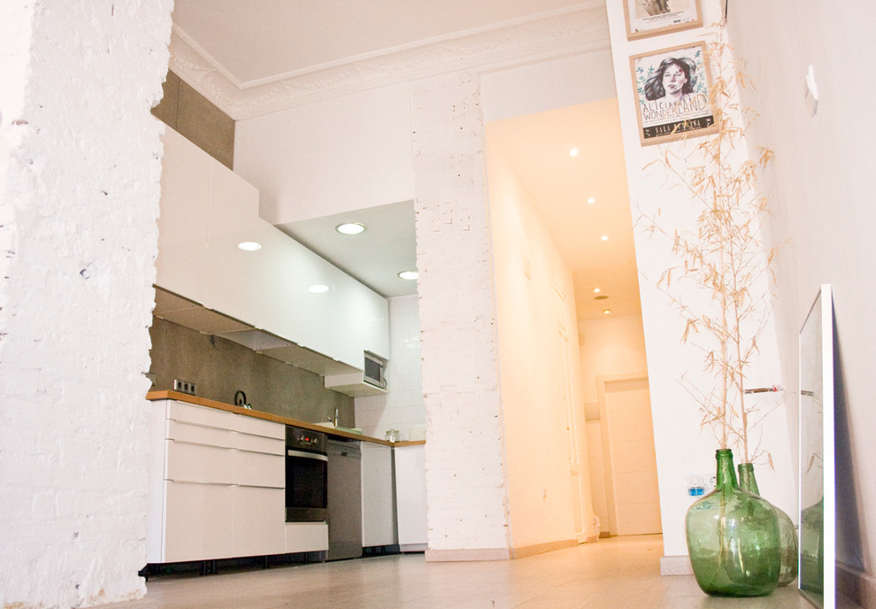 Bild på ett minimalistiskt kök med öppen planlösning, med vita skåp och träbänkskiva