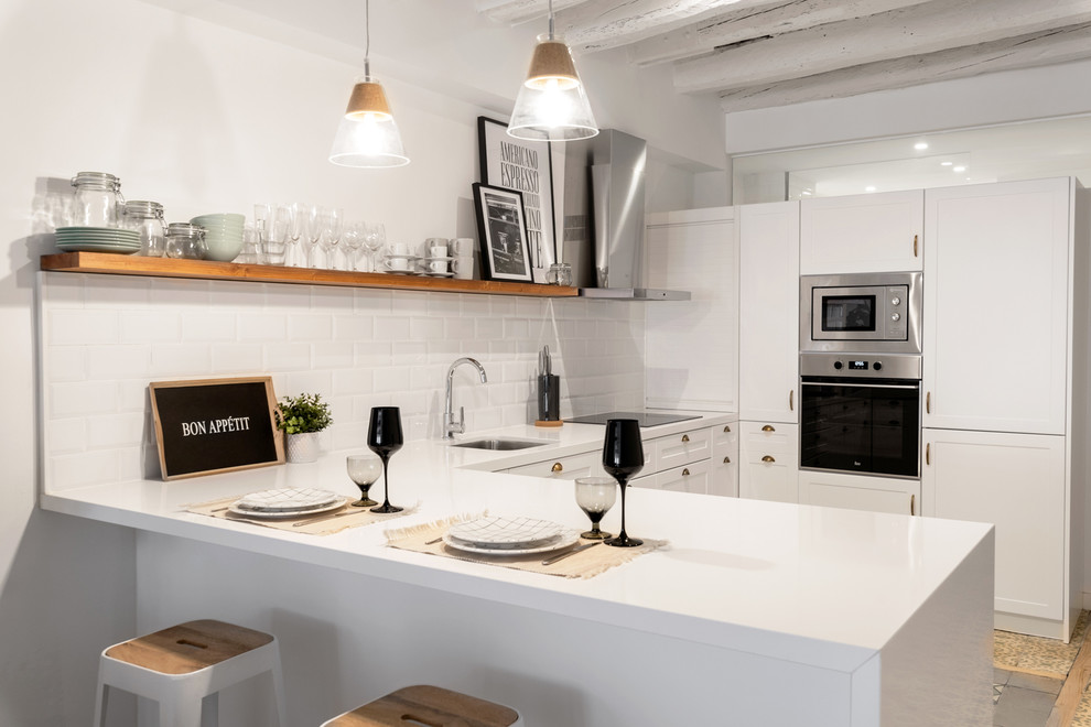 Bild på ett stort funkis vit vitt kök, med en undermonterad diskho, luckor med upphöjd panel, vita skåp, bänkskiva i kvarts, vitt stänkskydd, stänkskydd i keramik, integrerade vitvaror, cementgolv, en halv köksö och flerfärgat golv