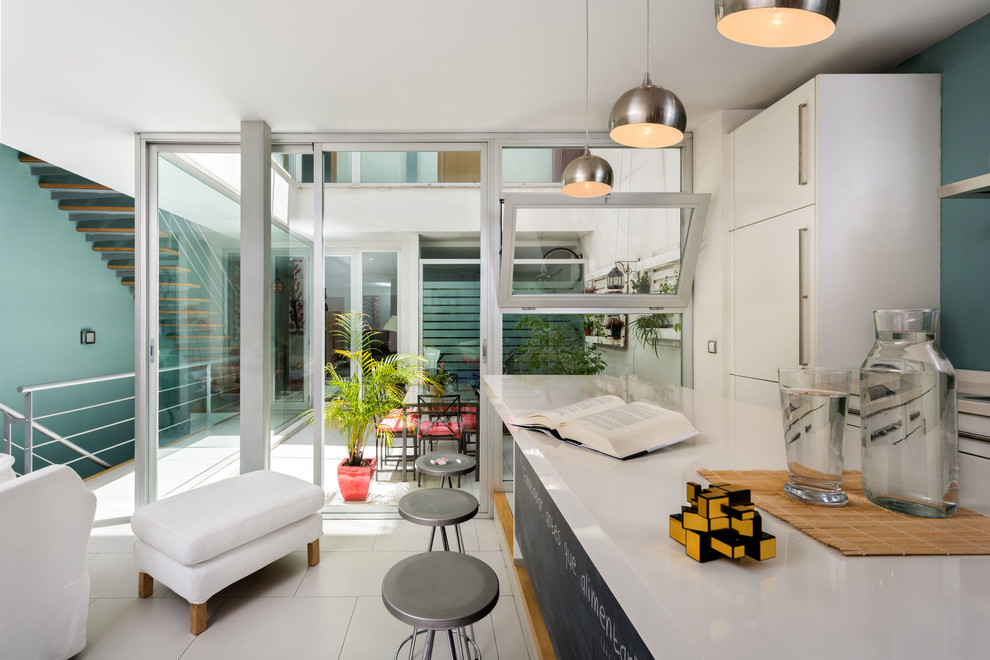 Ejemplo de cocina lineal moderna de tamaño medio abierta con armarios con paneles lisos, puertas de armario blancas, salpicadero azul, una isla y suelo blanco