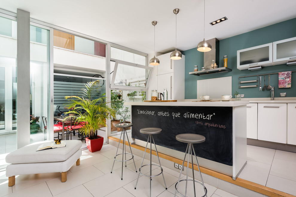 Offene, Einzeilige, Mittelgroße Moderne Küche mit flächenbündigen Schrankfronten, weißen Schränken, Küchenrückwand in Blau, Kücheninsel und weißem Boden in Sevilla