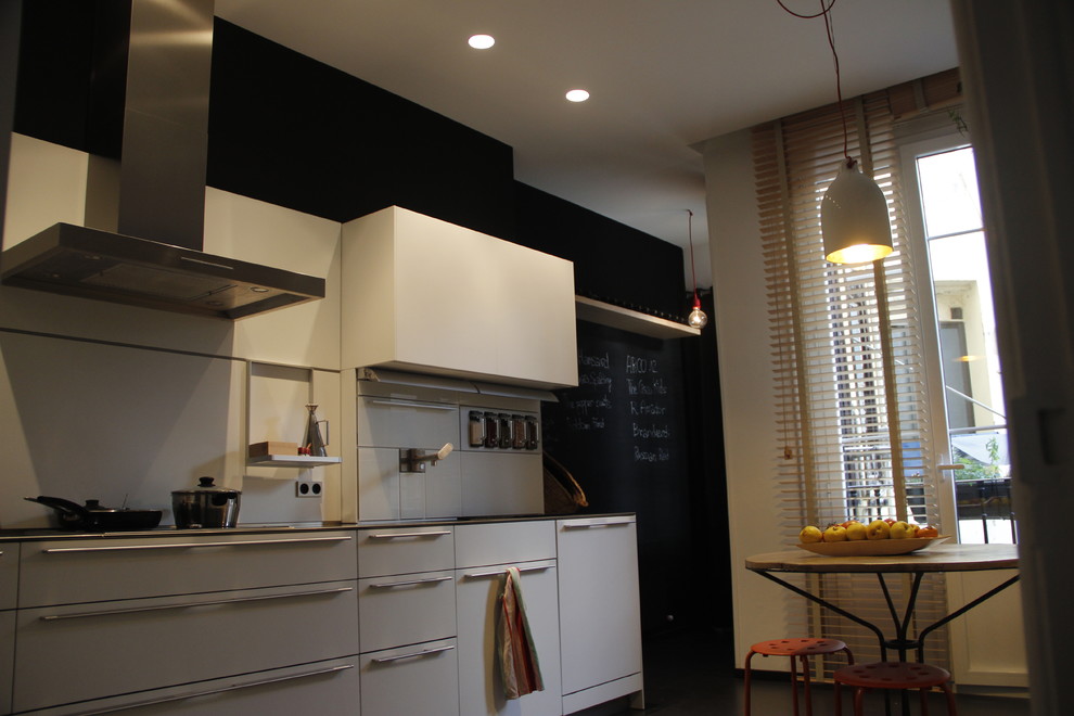 Imagen de cocinas en L contemporánea pequeña cerrada con puertas de armario blancas, encimera de laminado, electrodomésticos de acero inoxidable, fregadero bajoencimera y armarios con paneles lisos