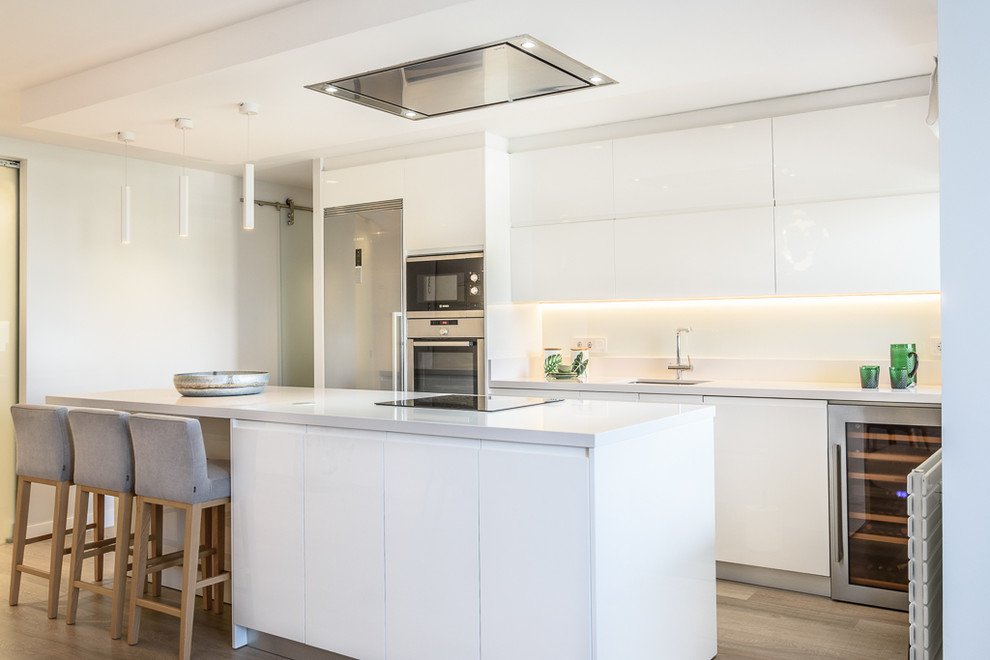 Diseño de cocina comedor lineal minimalista de tamaño medio con armarios con paneles lisos, puertas de armario blancas, salpicadero blanco y una isla