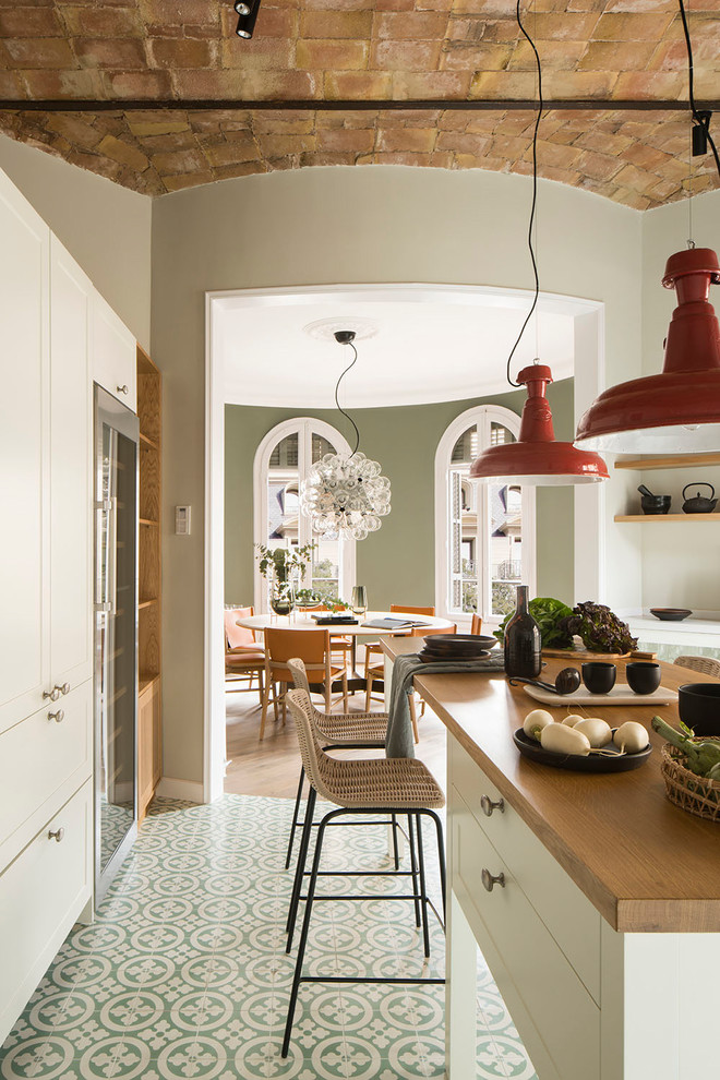 Eat-in kitchen - mid-sized transitional single-wall medium tone wood floor and brown floor eat-in kitchen idea in Barcelona with an integrated sink, raised-panel cabinets, white cabinets, wood countertops, white backsplash, limestone backsplash, stainless steel appliances, an island and brown countertops