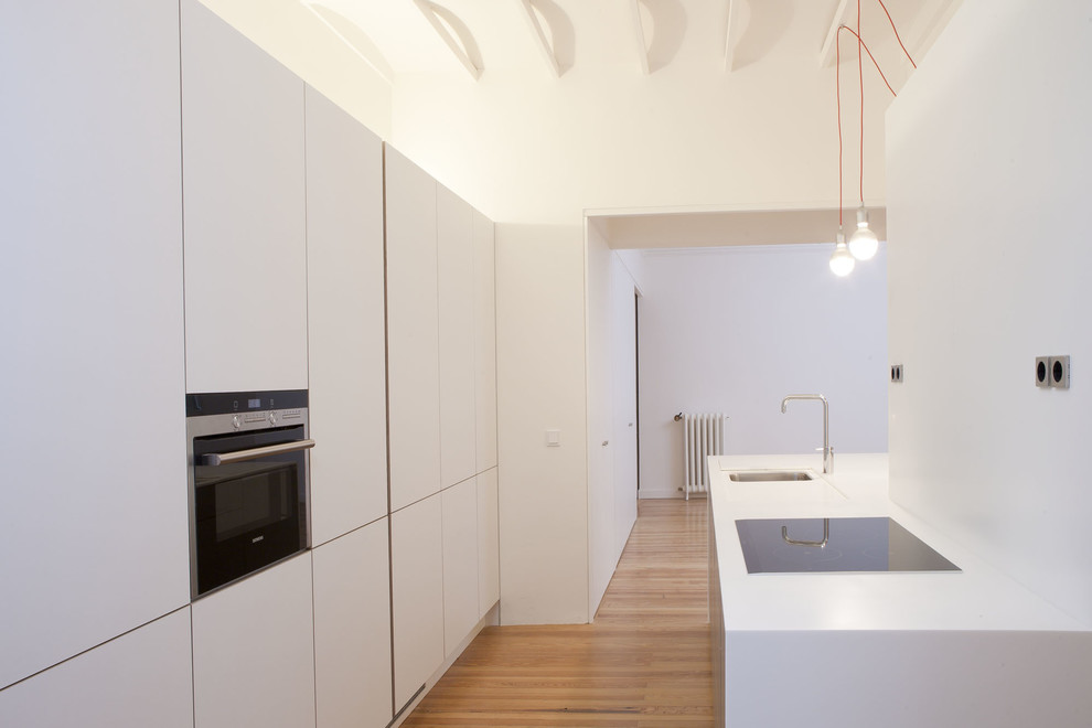 Стильный дизайн: прямая кухня-гостиная среднего размера в скандинавском стиле с одинарной мойкой, плоскими фасадами, белыми фасадами, техникой из нержавеющей стали, паркетным полом среднего тона и островом - последний тренд