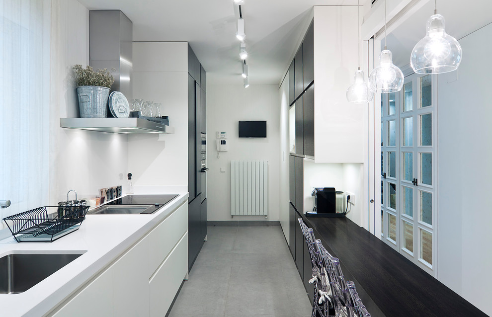 Inspiration for a mid-sized transitional galley enclosed kitchen remodel in Madrid with a single-bowl sink, flat-panel cabinets, white cabinets, white backsplash, stainless steel appliances and no island