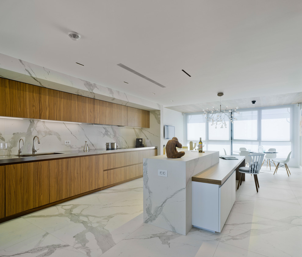 Cette photo montre une grande cuisine ouverte tendance en bois brun avec un placard à porte plane, plan de travail en marbre, une crédence blanche, une crédence en marbre, un sol en marbre, îlot et un sol blanc.