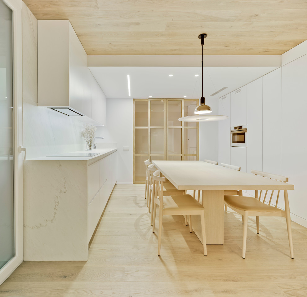 Idéer för mellanstora funkis linjära vitt kök och matrum, med släta luckor, vita skåp, vitt stänkskydd, vita vitvaror, ljust trägolv och beiget golv