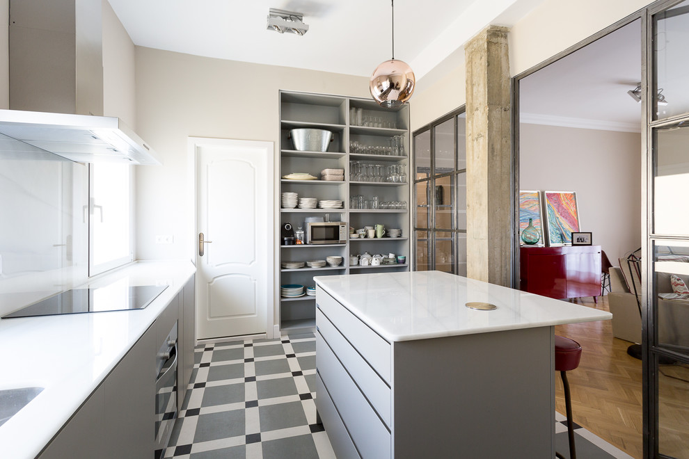 Cette image montre une cuisine linéaire design avec un placard à porte plane, des portes de placard grises, une crédence blanche, îlot, un plan de travail blanc et un sol gris.