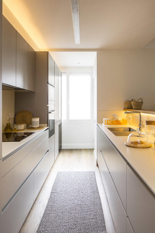 Ejemplo de cocina comedor escandinava de tamaño medio con armarios estilo shaker, puertas de armario blancas, electrodomésticos de acero inoxidable, suelo de madera en tonos medios y península