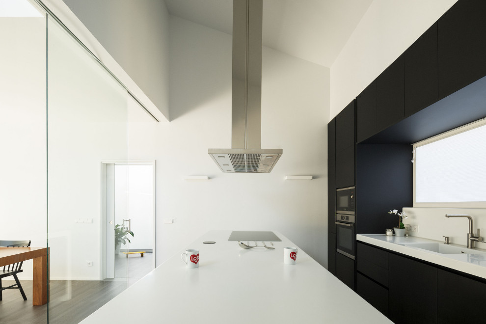 Idee per una cucina moderna con lavello integrato, ante lisce, paraspruzzi bianco, elettrodomestici neri e soffitto a volta
