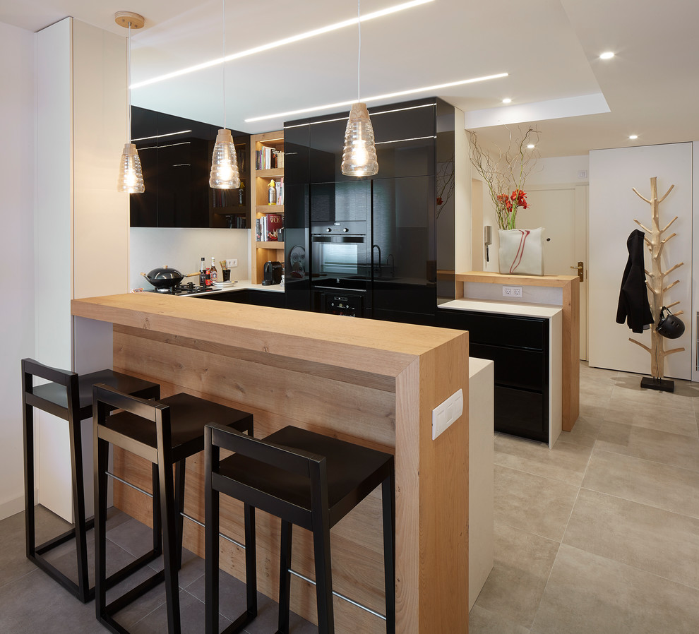 На фото: п-образная кухня-гостиная среднего размера в современном стиле с плоскими фасадами, черными фасадами, черной техникой, полом из керамической плитки и полуостровом с