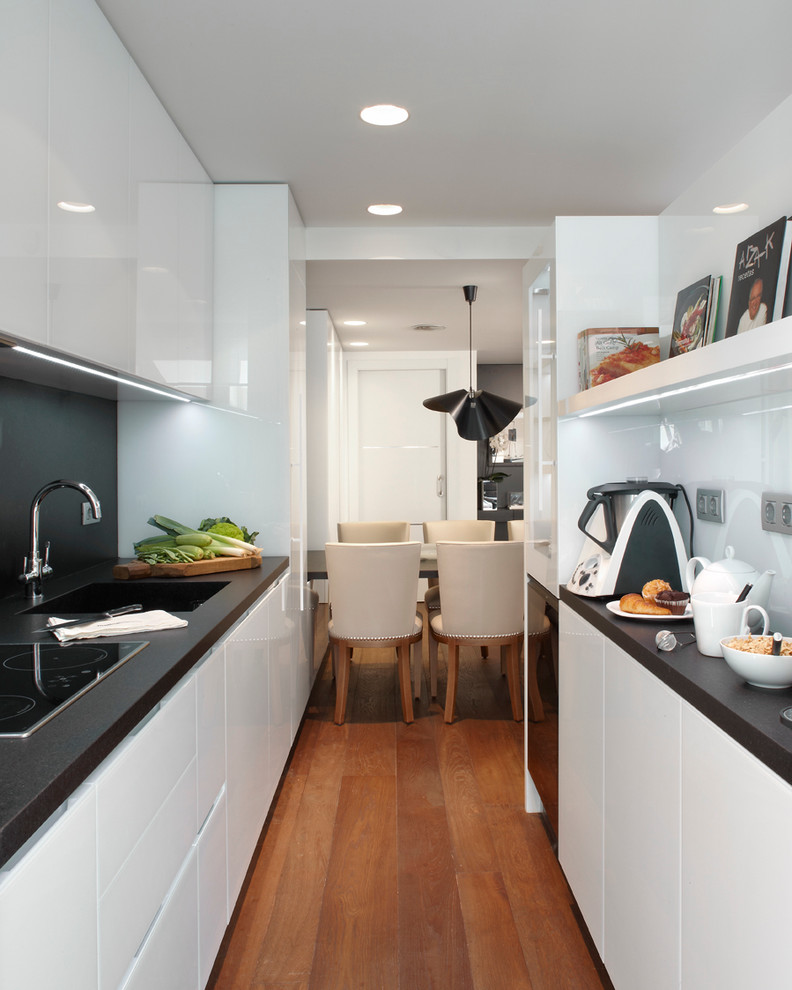 Mittelgroße Moderne Wohnküche ohne Insel in U-Form mit Waschbecken, flächenbündigen Schrankfronten, weißen Schränken und dunklem Holzboden in Barcelona