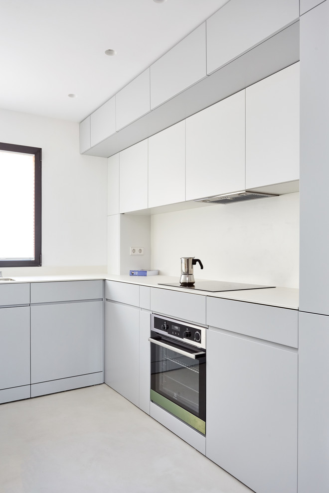 Idéer för ett litet nordiskt vit kök, med en undermonterad diskho, släta luckor, grå skåp, bänkskiva i kvarts, vitt stänkskydd, integrerade vitvaror, betonggolv och grått golv