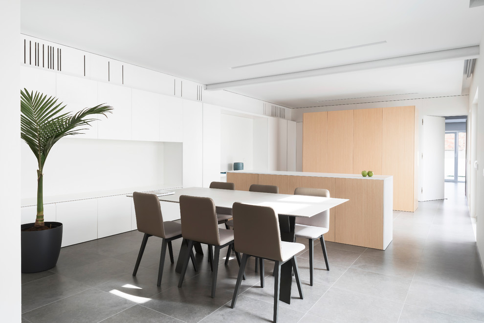 На фото: кухня-столовая в стиле модернизм с белыми стенами и серым полом