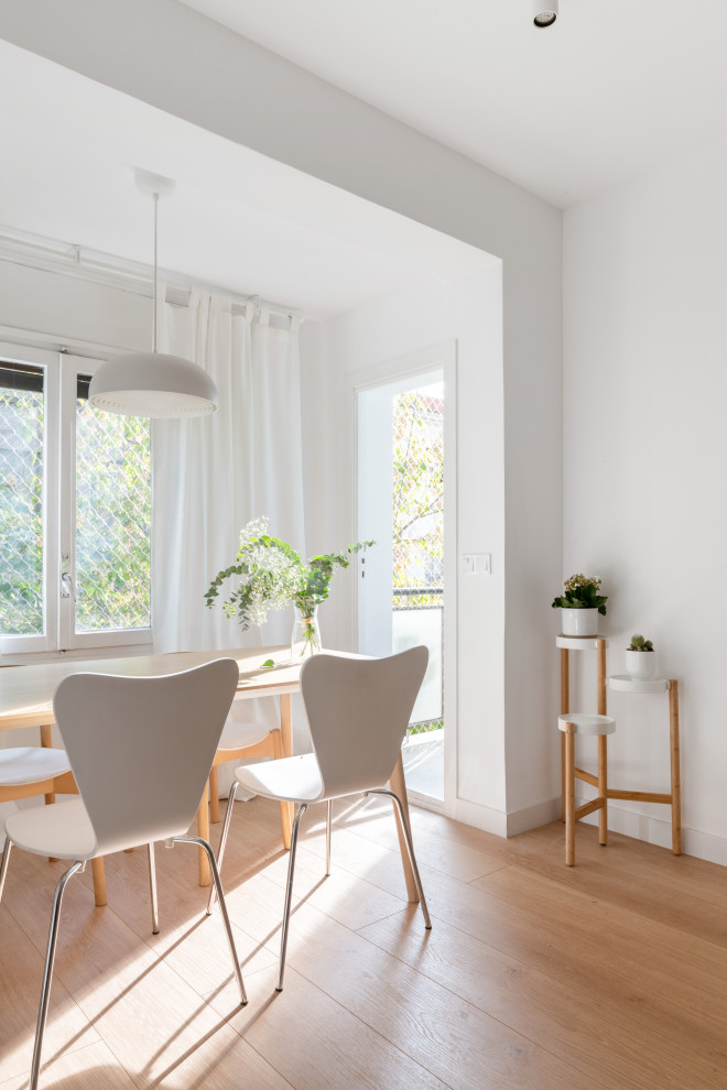 This is an example of a medium sized modern enclosed dining room in Madrid with white walls, light hardwood flooring and beige floors.