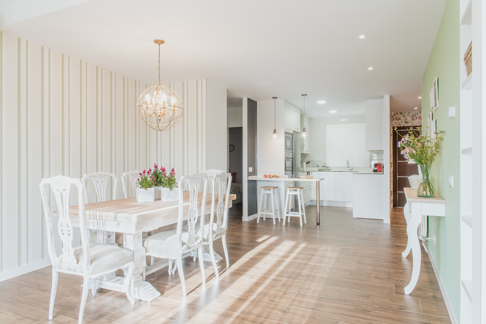 Cette image montre une salle à manger ouverte sur la cuisine style shabby chic avec un mur vert, un sol en bois brun et un sol marron.