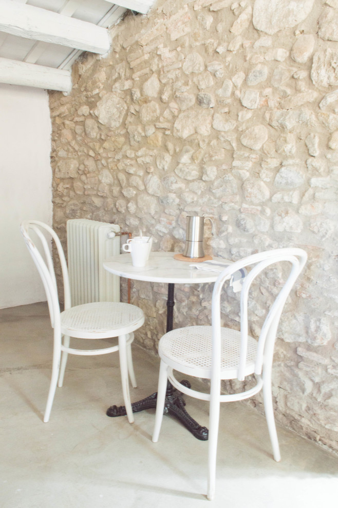 Medelhavsstil inredning av en liten matplats med öppen planlösning, med vita väggar, betonggolv och grått golv