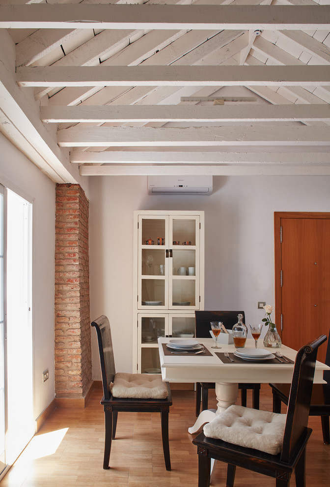 Imagen de comedor mediterráneo de tamaño medio abierto sin chimenea con paredes blancas y suelo de madera en tonos medios