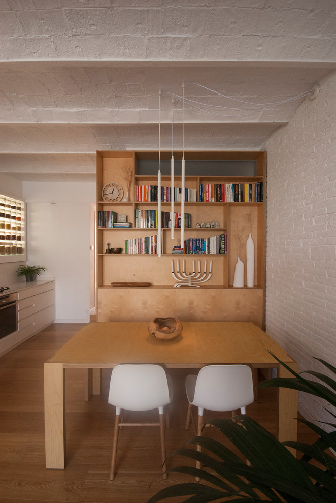 Modelo de comedor de cocina abovedado escandinavo de tamaño medio con paredes blancas, suelo de madera en tonos medios y ladrillo
