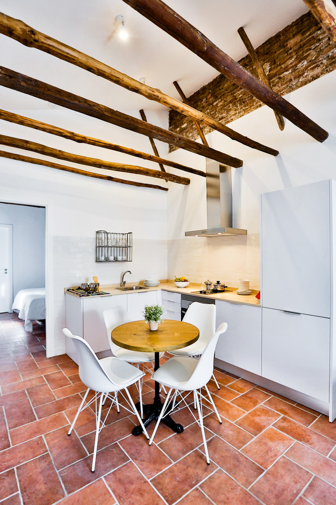Foto di una piccola sala da pranzo aperta verso la cucina mediterranea con pareti bianche, pavimento in terracotta e nessun camino