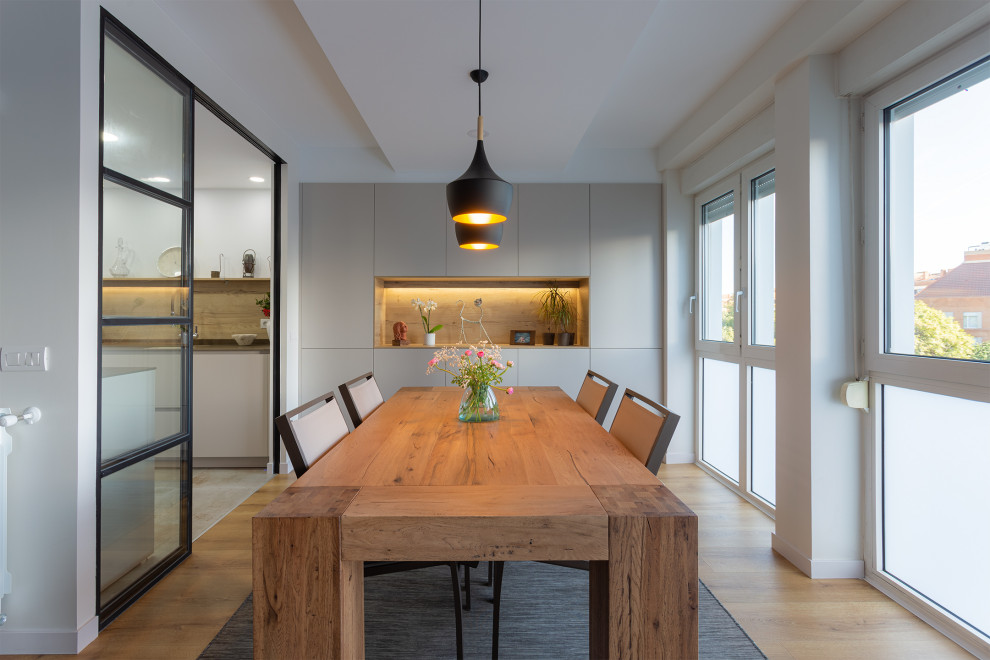 Ispirazione per una sala da pranzo aperta verso il soggiorno minimal di medie dimensioni con pareti bianche e pavimento marrone