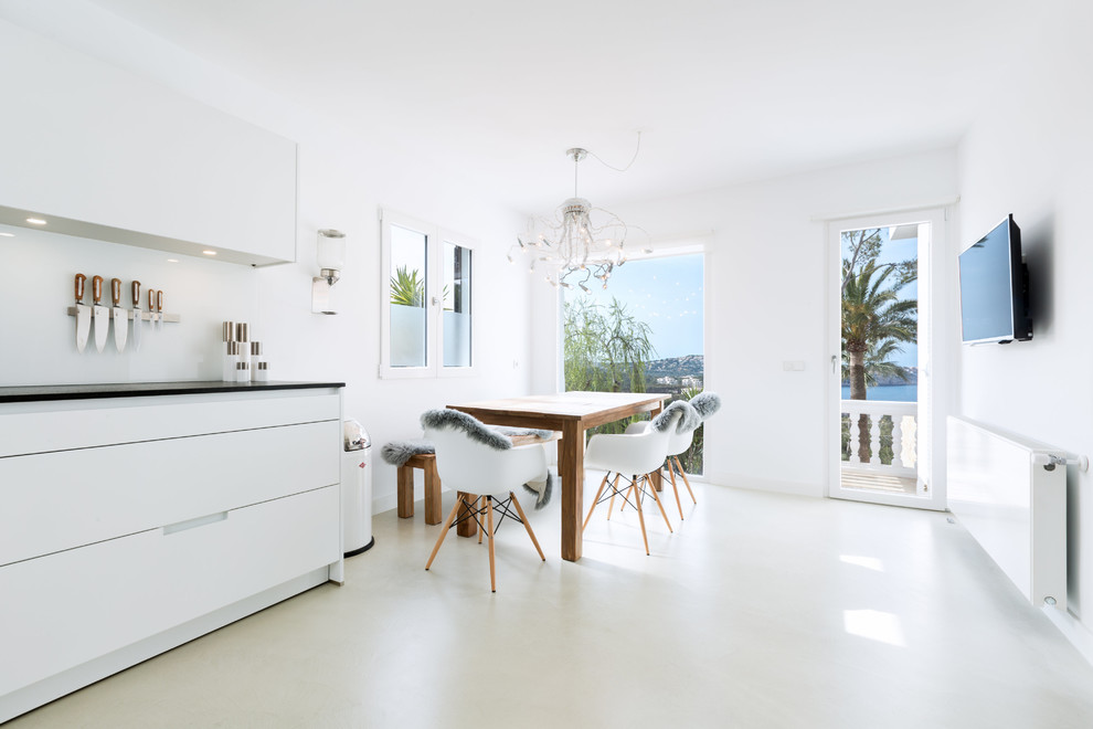 Immagine di una sala da pranzo aperta verso la cucina mediterranea di medie dimensioni con pareti bianche, pavimento in cemento e nessun camino