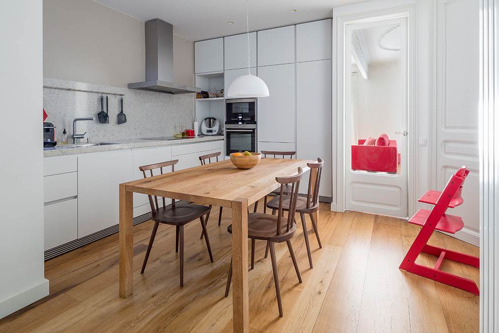 Mid-sized danish medium tone wood floor kitchen/dining room combo photo in Barcelona with white walls and no fireplace
