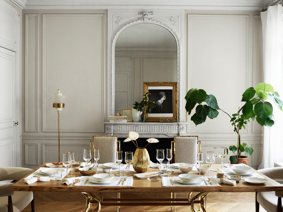 Inspiration pour une salle à manger ouverte sur le salon traditionnelle avec un mur blanc, un sol en bois brun, une cheminée standard et un manteau de cheminée en pierre.