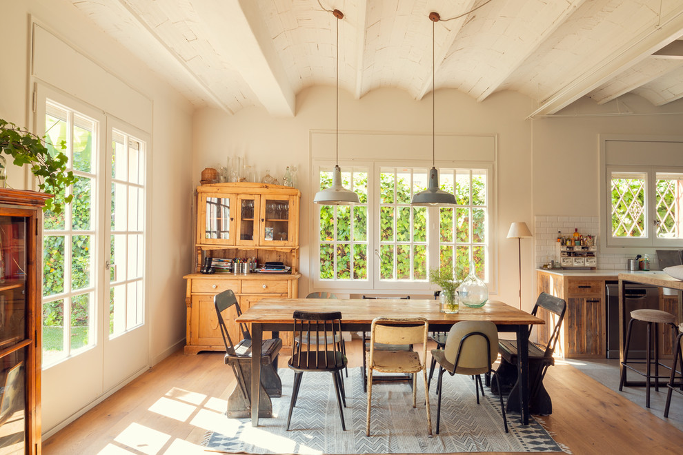 Immagine di una sala da pranzo aperta verso la cucina mediterranea con pareti bianche, pavimento in legno massello medio e pavimento marrone