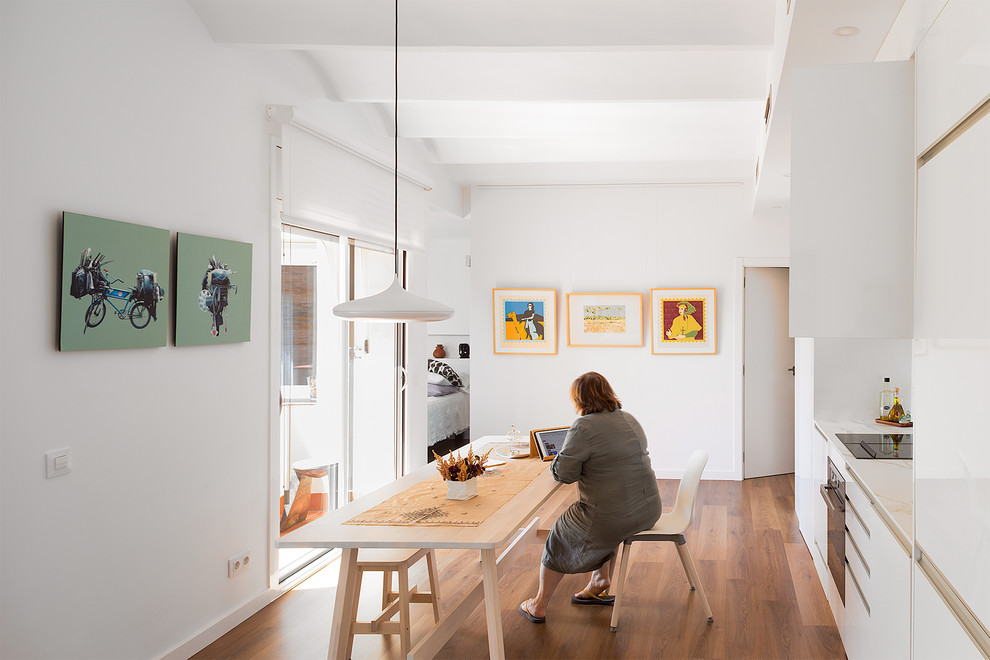 Idée de décoration pour une salle à manger ouverte sur la cuisine design de taille moyenne avec un mur blanc, un sol en bois brun et un sol marron.