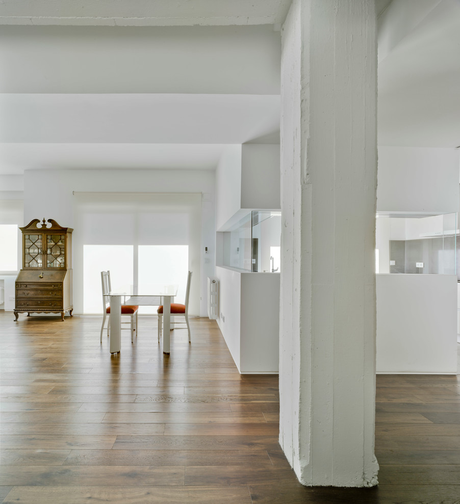 Foto di una grande sala da pranzo aperta verso il soggiorno minimal con pareti bianche, pavimento in legno massello medio e nessun camino